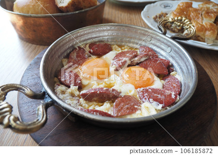 Turkish scrambled sausage eggs in copper pan 106185872