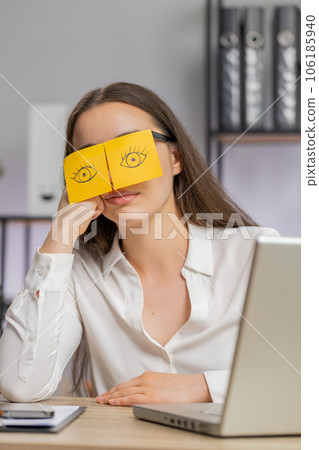 Inefficient tired lazy business woman working sleeping on laptop computer with eyes stickers on face 106185940