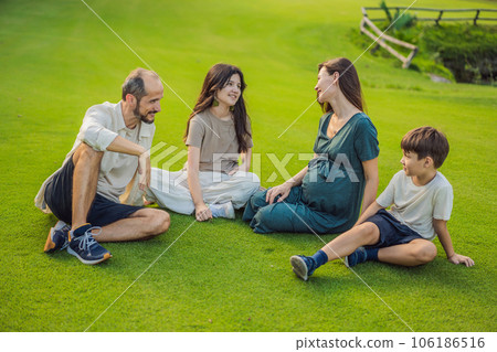 A loving family enjoying a leisurely walk in the park - a radiant pregnant woman after 40, embraced by her husband, and accompanied by their adult teenage children, savoring precious moments together 106186516