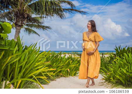 A radiant pregnant woman after 40 basking in the sun's warmth on a tropical beach, cherishing the serenity and bliss of her pregnancy journey 106186539