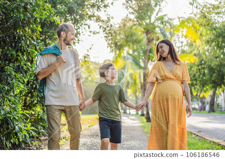 A loving family enjoying a leisurely walk in the park - a radiant pregnant woman after 40, embraced by her husband, and accompanied by their adult teenage son, savoring precious moments together A loving family enjoying a leisurely walk in the park - a radiant pregnant woman after 40, embraced by her husband, and accompanied by their adult teenage son, savoring precious moments together 106186546