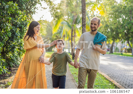A loving family enjoying a leisurely walk in the park - a radiant pregnant woman after 40, embraced by her husband, and accompanied by their adult teenage son, savoring precious moments together A loving family enjoying a leisurely walk in the park - a radiant pregnant woman after 40, embraced by her husband, and accompanied by their adult teenage son, savoring precious moments together 106186547