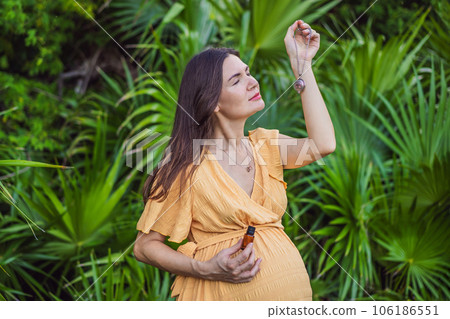 pregnant woman after 40 demonstrating the use of an aroma pendant, combining style and aromatherapy during her pregnancy journey 106186551