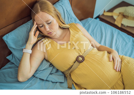 A stressed tired pregnant mother lying in bed at home. Morning sickness and nausea 106186552