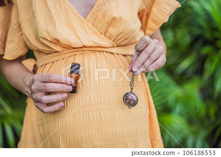 pregnant woman after 40 demonstrating the use of an aroma pendant, combining style and aromatherapy during her pregnancy journey 106186553