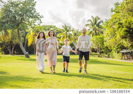 A loving family enjoying a leisurely walk in the park - a radiant pregnant woman after 40, embraced by her husband, and accompanied by their adult teenage children, savoring precious moments together A loving family enjoying a leisurely walk in the park - a radiant pregnant woman after 40, embraced by her husband, and accompanied by their adult teenage children, savoring precious moments together 106186554