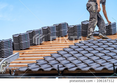 craftsman laying fired ceramic tiles on the roof craftsman laying fired ceramic tiles on the roof 106187312