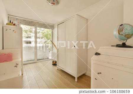a white room with wooden flooring and an earth globe on top of the cupboards in front of the door 106188659