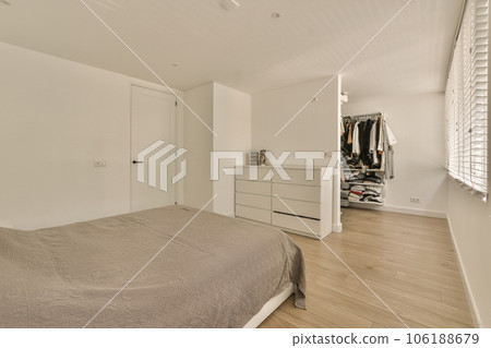 a bedroom with white walls and wood flooring, including a large bed in the center of the room is an open closet a bedroom with white walls and wood flooring, including a large bed in the center of the room is an open closet 106188679