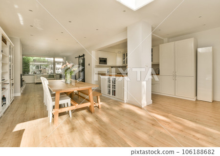 a kitchen and dining area in a house with wood floors, white cabinets and an open floor to the living room 106188682