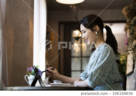 Profile of a young woman using a tablet in a cafe Profile of a young woman using a tablet in a cafe 106189636