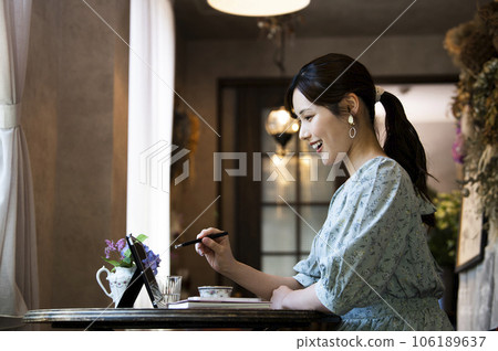 一位年輕女子在咖啡館使用平板電腦的個人資料 106189637