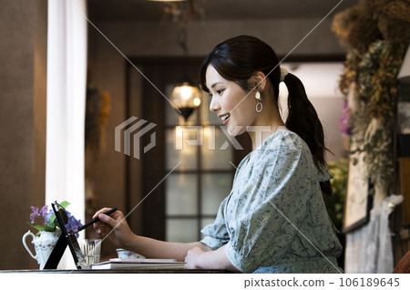 Profile of a young woman using a tablet in a cafe Profile of a young woman using a tablet in a cafe 106189645