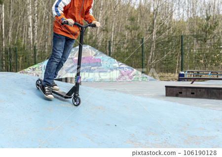 A happy Boy rides a stunt scooter in a skatepark. A happy Boy rides a stunt scooter in a skatepark. 106190128