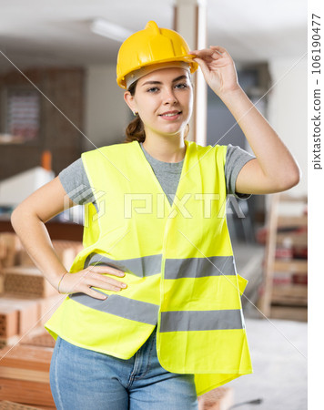 Smiling female civil engineer in yellow uniform at construction site 106190477
