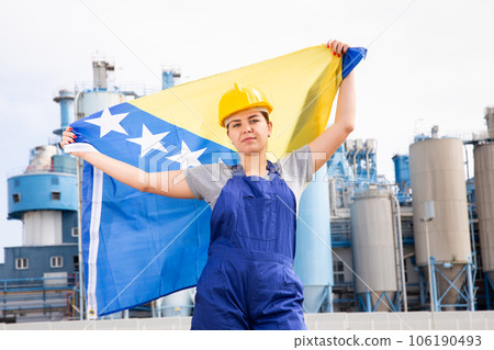 Worried girl in work clothes and hardhat with flag of bosnia standing in front of industrial scenery Worried girl in work clothes and hardhat with flag of bosnia standing in front of industrial scenery 106190493