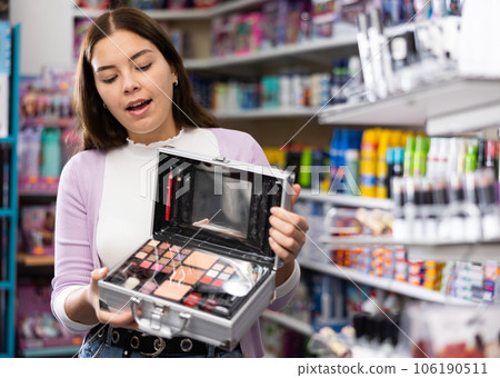 Surprised girl choosing travel cosmetics set at cosmetics department 106190511