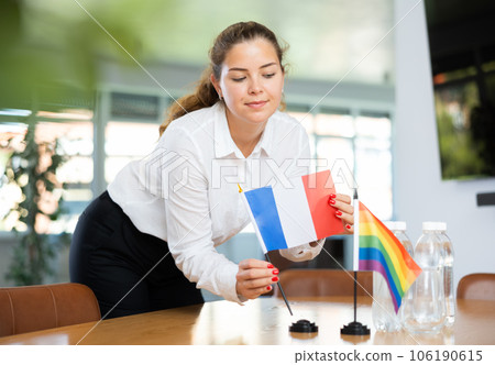 Young lady sets miniatures flags of LGBT and France before international negotiations 106190615