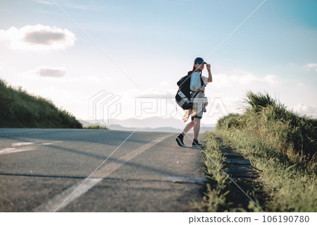 Female backpacker walking on the road 106190780