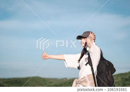 Woman with a backpack hitchhiking 106191081