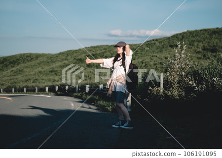 Woman with a backpack hitchhiking 106191095