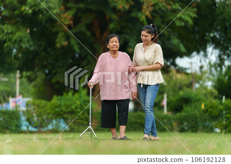granddaughter and senior woman with walking stick in the grass field at park granddaughter and senior woman with walking stick in the grass field at park 106192128