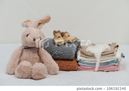 stack of baby clothes and shoes and toy on bed stack of baby clothes and shoes and toy on bed 106192140