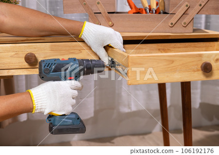 Worker repair wooden drawer of cabinet in living room. 106192176