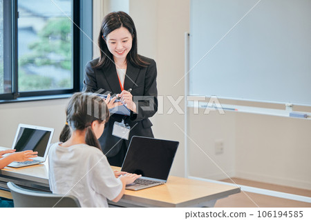 A young cram school teacher watching over the study of elementary school students 106194585