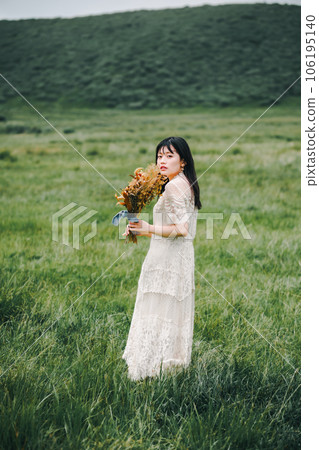 A woman in a white dress holding a bouquet in the meadow 106195140
