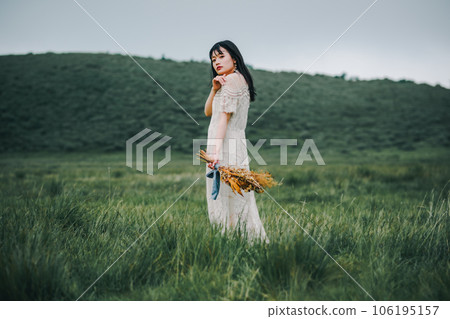A woman in a white dress holding a bouquet in the meadow A woman in a white dress holding a bouquet in the meadow 106195157