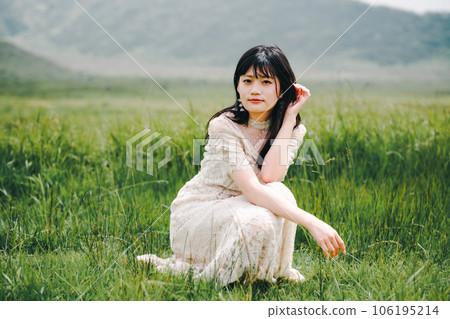 一個穿著白色連衣裙的女人蹲在草地上 106195214