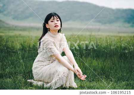 A woman in a white dress crouching on a meadow A woman in a white dress crouching on a meadow 106195215