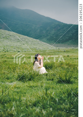 A woman in a white dress crouching on a meadow A woman in a white dress crouching on a meadow 106195223