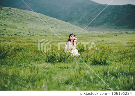 A woman in a white dress crouching on a meadow 106195224
