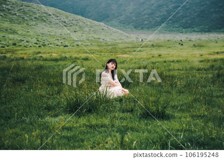 一個穿著白色連衣裙的女人蹲在草地上 一個穿著白色連衣裙的女人蹲在草地上 106195248