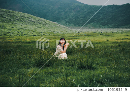 一個穿著白色連衣裙的女人蹲在草地上 106195249
