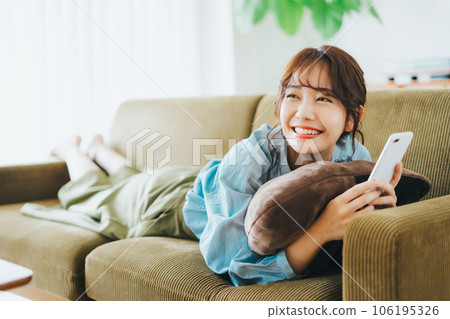 一個女人躺在沙發上，拿著智能手機 106195326