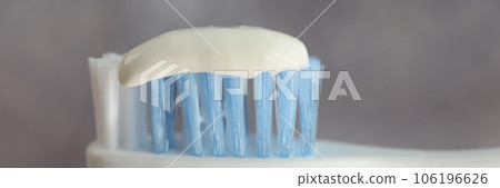 Close up of toothpaste on toothbrush on gray background. 106196626