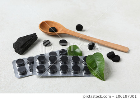 A wooden spoon with activated charcoal tablets and leaves A wooden spoon with activated charcoal tablets and leaves 106197301