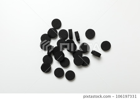 Tablets of activated carbon on a light background 106197331