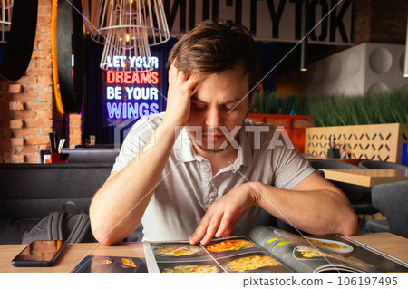 young caucasian male man reading menu in restaurant. difficult choice concept, portrait 106197495