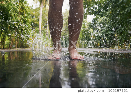 Man jumping with bare feet into puddle 106197561