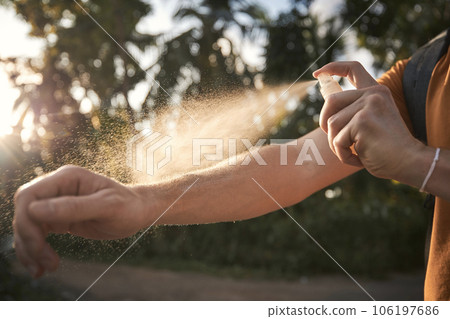 Man is applying insect repellent on his hand. 106197686