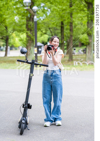A young and cute woman who takes a hobby camera while moving on an electric kickboard | Image of a camera girl 106197758