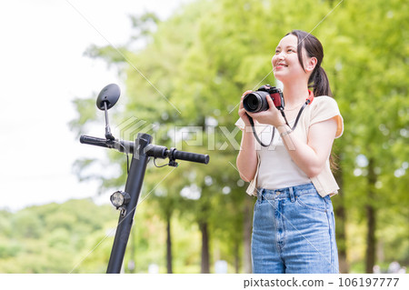 A young and cute woman who takes a hobby camera while moving on an electric kickboard | Image of a camera girl 106197777