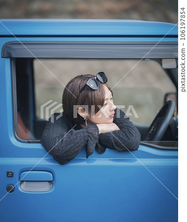 A woman with sunglasses on her head looks out from the driver's seat of a blue car A woman with sunglasses on her head looks out from the driver's seat of a blue car 106197854