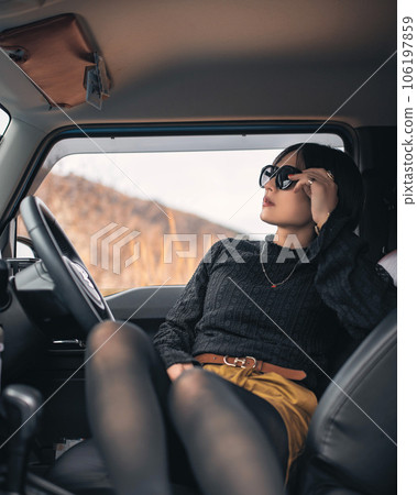 A woman putting her foot on the passenger side and putting her hand on her sunglasses A woman putting her foot on the passenger side and putting her hand on her sunglasses 106197859