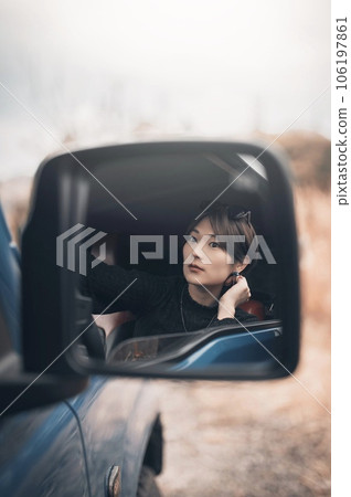 Woman in the driver's seat through the rear-view mirror of the car Woman in the driver's seat through the rear-view mirror of the car 106197861