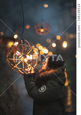 A woman closing her eyes with a ball lantern in the background 106199314